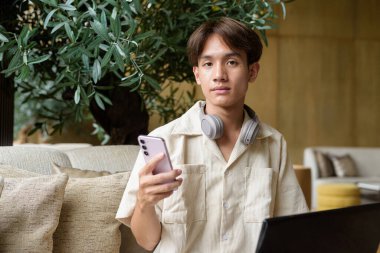 Modern kahve dükkanında oturan Asyalı yakışıklı olmayan çift yönlü öğrenci.