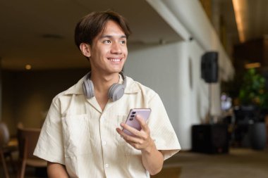 Modern kahve dükkanında oturan Asyalı yakışıklı olmayan çift yönlü öğrenci.