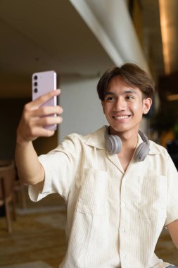 Modern kahve dükkanında oturan Asyalı yakışıklı olmayan çift yönlü öğrenci.