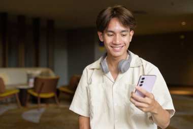 Modern kahve dükkanında oturan Asyalı yakışıklı olmayan çift yönlü öğrenci.