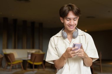 Modern kahve dükkanında oturan Asyalı yakışıklı olmayan çift yönlü öğrenci.