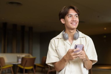 Modern kahve dükkanında oturan Asyalı yakışıklı olmayan çift yönlü öğrenci.