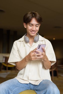 Modern kahve dükkanında oturan Asyalı yakışıklı olmayan çift yönlü öğrenci.