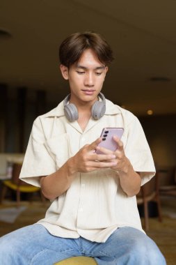 Modern kahve dükkanında oturan Asyalı yakışıklı olmayan çift yönlü öğrenci.