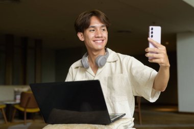 Modern kahve dükkanında oturan Asyalı yakışıklı olmayan çift yönlü öğrenci.