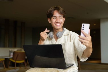 Modern kahve dükkanında oturan Asyalı yakışıklı olmayan çift yönlü öğrenci.