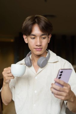 Modern kahve dükkanında oturan Asyalı yakışıklı olmayan çift yönlü öğrenci.