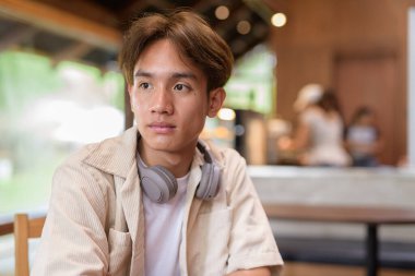 Cafe restoranında oturan yakışıklı, Asyalı, ikili olmayan genç adam.