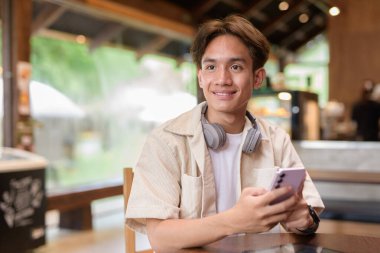 Cafe restoranında oturan yakışıklı, Asyalı, ikili olmayan genç adam.