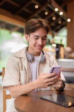 Cafe restoranında oturan yakışıklı, Asyalı, ikili olmayan genç adam.