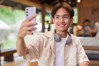 Cafe restoranında oturan yakışıklı, Asyalı, ikili olmayan genç adam.