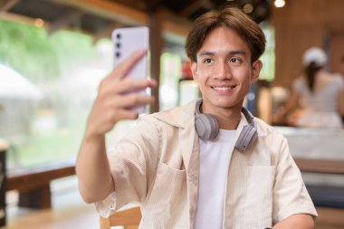 Cafe restoranında oturan yakışıklı, Asyalı, ikili olmayan genç adam.