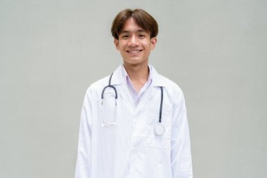 Genç Asyalı sağlık çalışanı laboratuvar önlüğü giyiyor.