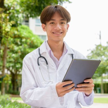 Genç Asyalı sağlık çalışanı laboratuvar önlüğü giyiyor.