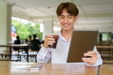 Üniversite kampüsünde dijital tablet bilgisayarla çalışan Asyalı olmayan ikili üniversite öğrencisi.