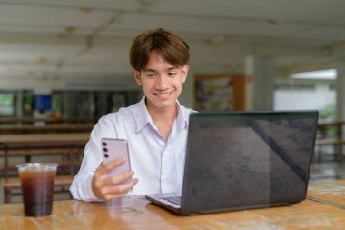 Üniversite kampüsünde bilgisayar ve telefon kullanan Asyalı olmayan ikili üniversite öğrencisi.