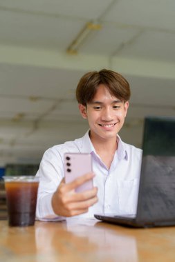 Üniversite kampüsünde bilgisayar ve telefon kullanan Asyalı olmayan ikili üniversite öğrencisi.