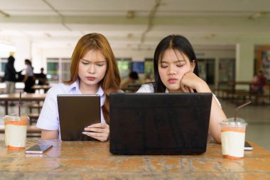 İki Taylandlı kız öğrenci açık havada bir üniversite kafesinde oturuyor. Arkadaşlık ya da çift sahnesi, gündelik yaşam tarzı, eğitim ve gençlik kültürü.