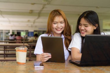 İki Taylandlı kız öğrenci açık havada bir üniversite kafesinde oturuyor. Arkadaşlık ya da çift sahnesi, gündelik yaşam tarzı, eğitim ve gençlik kültürü.