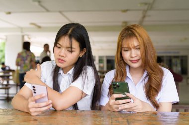 İki Taylandlı kız öğrenci açık havada bir üniversite kafesinde oturuyor. Arkadaşlık ya da çift sahnesi, gündelik yaşam tarzı, eğitim ve gençlik kültürü.