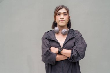 Açık hava duvarının önünde spor kıyafetler giymiş transseksüel bir Asyalı kadının portresi.