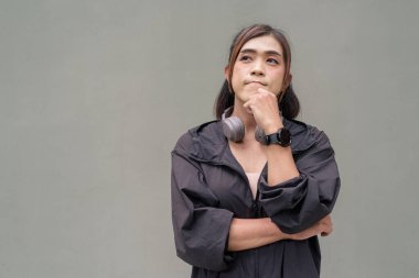 Açık hava duvarının önünde spor kıyafetler giymiş transseksüel bir Asyalı kadının portresi.