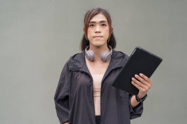 Açık hava duvarının önünde spor kıyafetler giymiş transseksüel bir Asyalı kadının portresi.