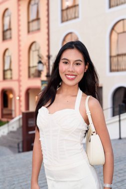 Avrupa tarzı bir kasabada uzun siyah saçlı güzel bir Asyalı kadının portresi. Açık havada zarif bir bayan turist, Avrupa tarzı mimari ve çekiciliğin tadını çıkarıyor..