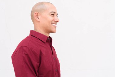 Burgonya gömlekli, beyaz arka planda duran kendine güvenen kel, yetişkin bir adam. Stüdyo portre tarzı, temiz, minimal, profesyonel görünüm..
