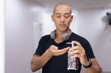 Spor salonundan sonra kel latin adam ellerini sıvı sabunla yıkıyor. Hijyen, temizlik ve sağlık konsepti. Temiz yaşam tarzı, kişisel bakım alışkanlıkları ve kapalı alanda bakım..