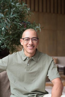 40 'lı yaşlarda Latin bir adam otel kafesinde ya da barda modern iç mimari ile poz veriyor. Vesikalık, zarif iş-gündelik görünüş, rahat tavır, güven ve yakışıklı olgun erkeklik üzerine odaklanmış..