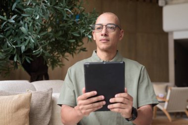 Zarif bir kafeteryada, otel barında veya restoranda şık, kel bir İspanyol 'un internet tabletine bakması. Dijital yaşam tarzı, iş seyahati sırasında gelişigüzel teknolojik kullanım ya da modern çevrede boş zamanlar.