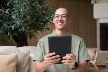 Zarif bir kafeteryada, otel barında veya restoranda şık, kel bir İspanyol 'un internet tabletine bakması. Dijital yaşam tarzı, iş seyahati sırasında gelişigüzel teknolojik kullanım ya da modern çevrede boş zamanlar.