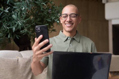 Gözlüklü, 40 'lı yaşlarda kel bir adam otel kafede ya da barda dizüstü bilgisayarla çalışıyor. Uzak iş işleri, seyahat verimliliği, dijital göçebe yaşam tarzı, iş kıyafeti ve odaklanmış tavır..