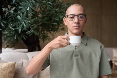 Otel kafesinde ya da dinlenme odasında oturan olgun kel bir adam elinde kahve ya da çay tutuyordu. Konukseverliği yansıtır, sakin bir tatil, zarif bar dekorasyonu, günlük iş ve sağlık yaşam tarzını yansıtır..