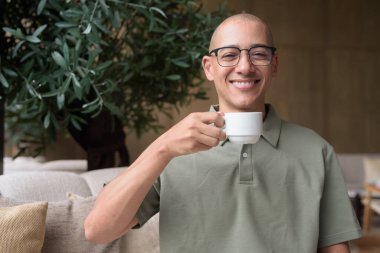 Otel kafesinde ya da dinlenme odasında oturan olgun kel bir adam elinde kahve ya da çay tutuyordu. Konukseverliği yansıtır, sakin bir tatil, zarif bar dekorasyonu, günlük iş ve sağlık yaşam tarzını yansıtır..