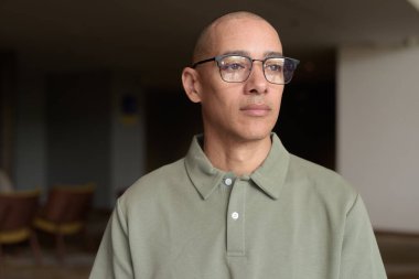 40 'lı yaşlarda Latin bir adam otel kafesinde ya da barda modern iç mimari ile poz veriyor. Vesikalık, zarif iş-gündelik görünüş, rahat tavır, güven ve yakışıklı olgun erkeklik üzerine odaklanmış..