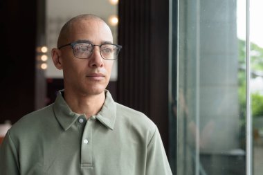 40 'lı yaşlarda Latin bir adam otel kafesinde ya da barda modern iç mimari ile poz veriyor. Vesikalık, zarif iş-gündelik görünüş, rahat tavır, güven ve yakışıklı olgun erkeklik üzerine odaklanmış..