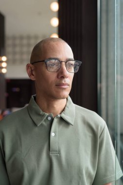 40 'lı yaşlarda Latin bir adam otel kafesinde ya da barda modern iç mimari ile poz veriyor. Vesikalık, zarif iş-gündelik görünüş, rahat tavır, güven ve yakışıklı olgun erkeklik üzerine odaklanmış..