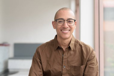 40 'lı yaşlarda kel bir adam kafeteryada oturuyor, günlük gömlek ve gözlük takıyor. Kendinden emin ve mutlu bir ifade. Kentsel yaşam tarzı, modern adam, rahat ortamda yetişkin portresi.