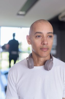 Modern spor salonunda kendine güvenen kel Latin bir adam. Sağlık, eğitim disiplini ve ev ortamında güçlü ve sağlıklı bir yaşam tarzının portresi..