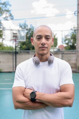 Spor giyimli kel adam basketbol sahasında poz veriyor. Kentsel spor yaşam tarzı, özgüven, atletizm ve sağlıklı açık hava spor atmosferi..