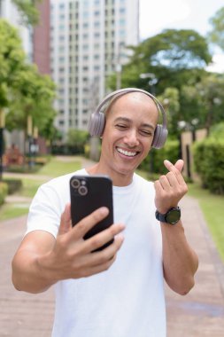 Parkta ya da şehir merkezinde yürürken telefonu kullanan kel bir İspanyol. Modern dijital yaşam tarzını, sağlıklı hareket alışkanlıklarını ve açık hava dengesini temsil eder..