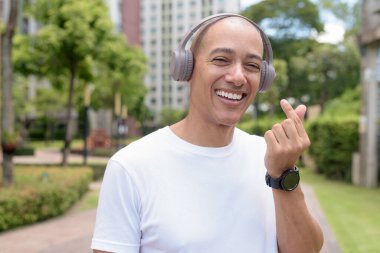 Şehir veya park alanında yürüyen kel Latin bir adam, açık hava hareketinin tadını çıkarıyor. Kendine güvenen sağlık yaşam tarzı, aktif alışkanlıklar ve sağlıklı yaz kentsel rutinini yakalar.