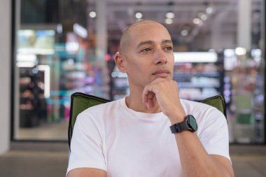 40 'lı yaşlarda İspanyol bir adam açık hava kahve dükkanında kendine güvenerek poz veriyor. Sıcak, sağlıklı, rahat bir portre modern şehir yaşam tarzını ve kişiliğini doğal ışık altında gösteriyor..