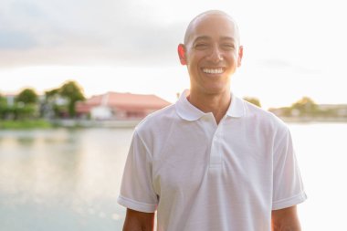 Kel yakışıklı İtalyan adamın yaz portresi. Gün batımında park gölünün yanında objektifle parlıyor.