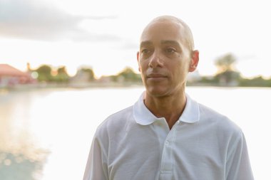 Kel yakışıklı İtalyan adamın yaz portresi. Gün batımında park gölünün yanında objektifle parlıyor.