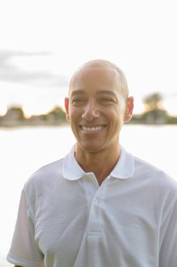 Kel yakışıklı İtalyan adamın yaz portresi. Gün batımında park gölünün yanında objektifle parlıyor.