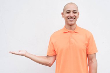 Orta yaşlı, turuncu polo tişörtlü, beyaz duvarlı yakışıklı bir İspanyol 'un stüdyo portresi. Günlük yaşam tarzı ve moda konsepti.