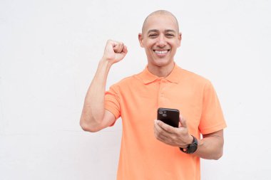 Orta yaşlı, turuncu polo tişörtlü, beyaz duvarlı yakışıklı bir İspanyol 'un stüdyo portresi. Günlük yaşam tarzı ve moda konsepti.